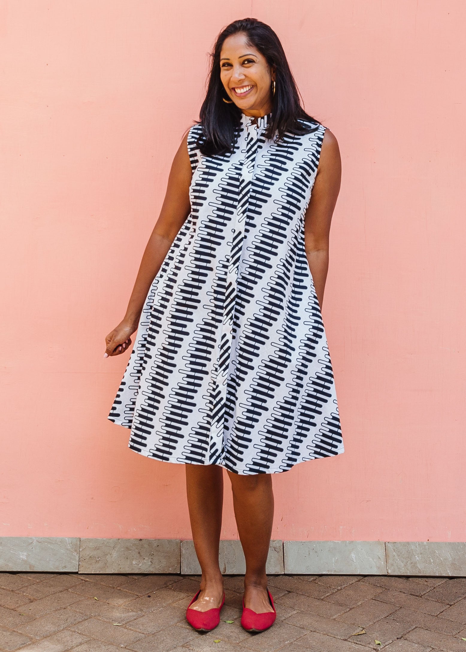 Model wearing white sleevless dress with black and white zigzag print.