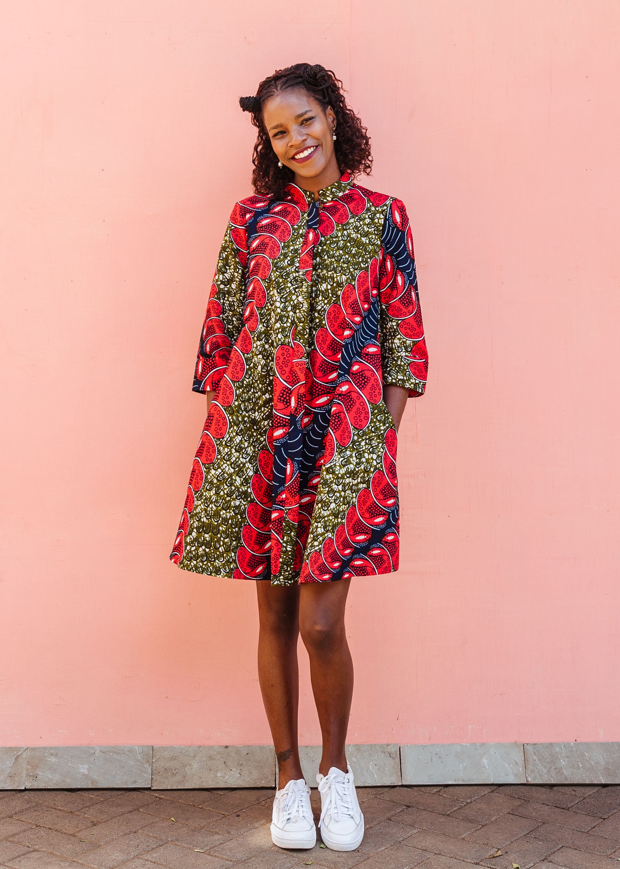 Model wearing green dress, with bold red and navy bauble print.