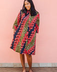 Model wearing green dress, with bold red and navy bauble print.