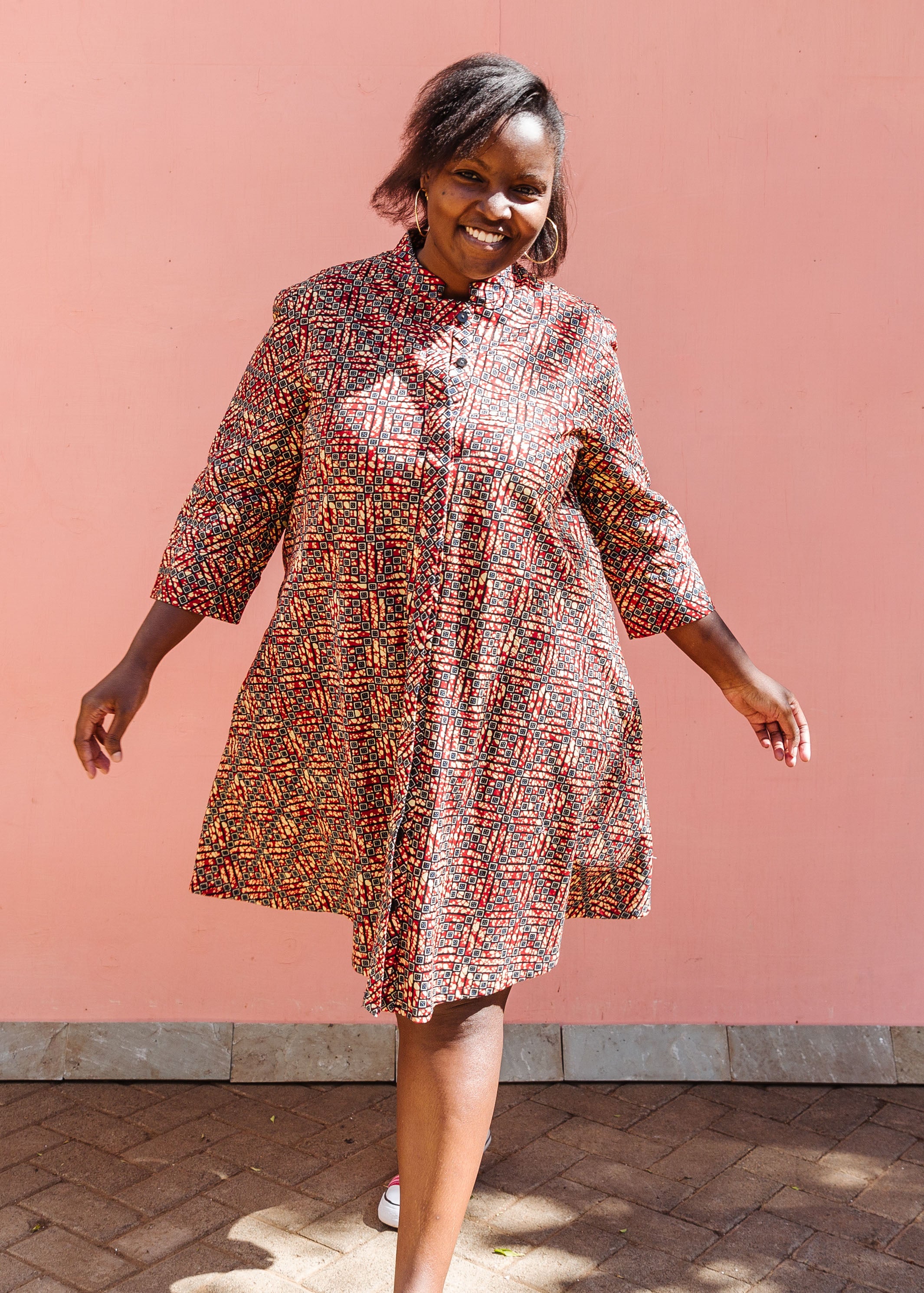 Model wearing red, navy and white mosaic print dress.