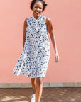 Model wearing white sleeveless dress with blue floral print.