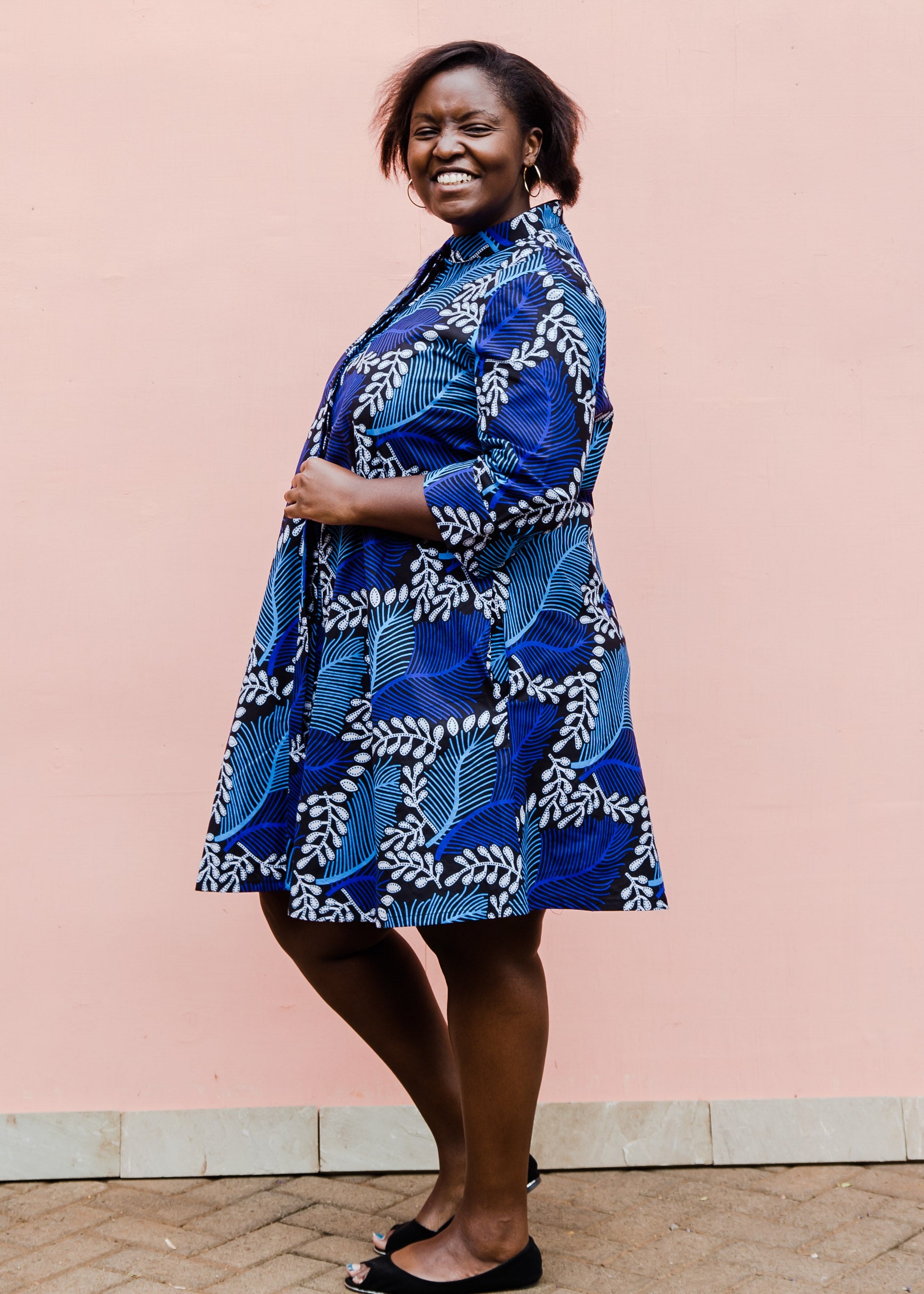Model wearing blue floral print dress, paired with black flats.