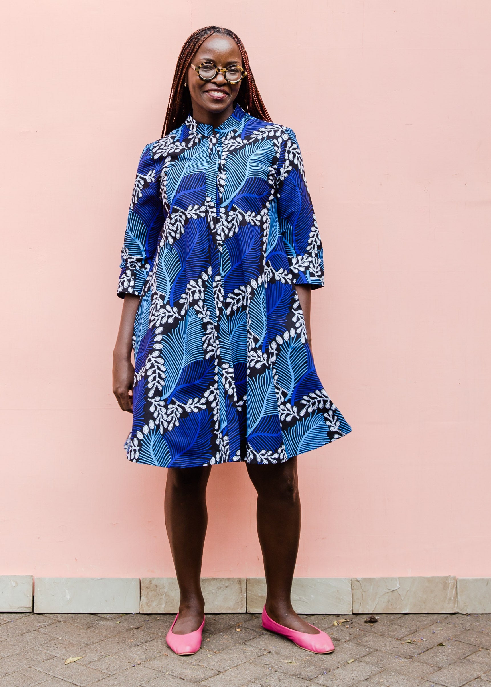 Model wearing blue floral print dress, paired with pink flats.