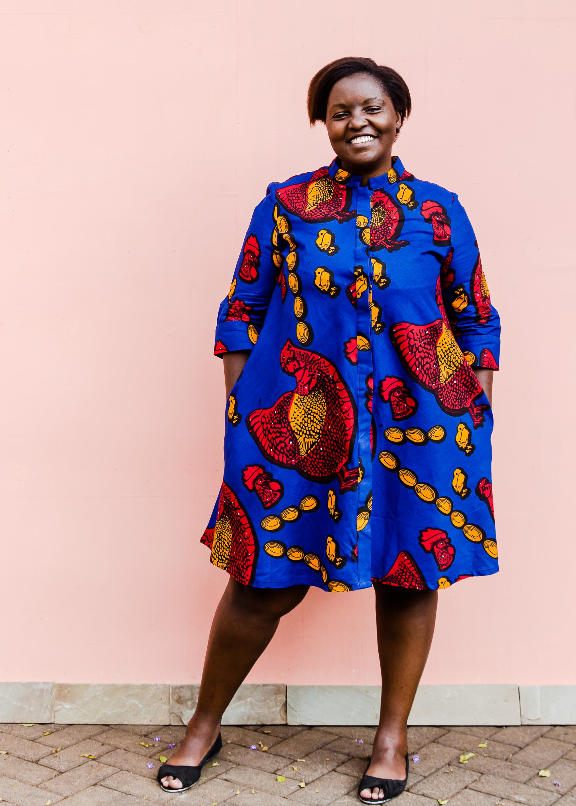 model wearing a rooster and chick design dress in blue, red and orange