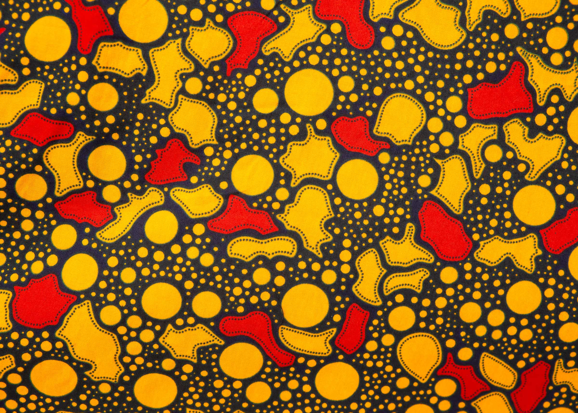Close up display of black dress with yellow and red small blob print, fabric.