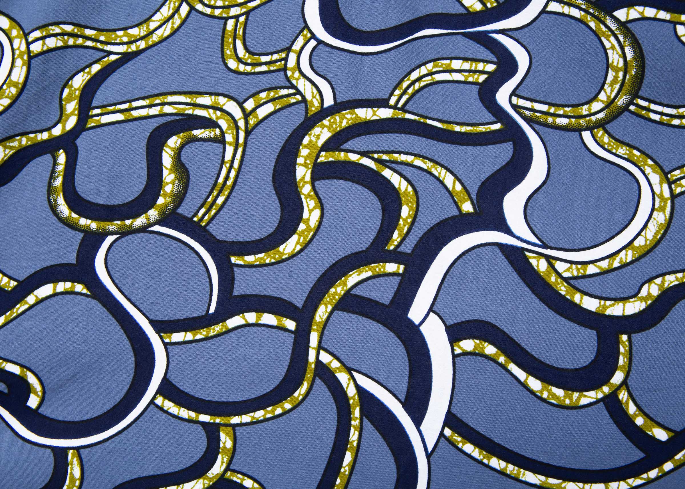 Close up display of blue sleeveless dress with green, white and navy squiggle design.