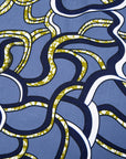 Close up display of blue sleeveless dress with green, white and navy squiggle design.