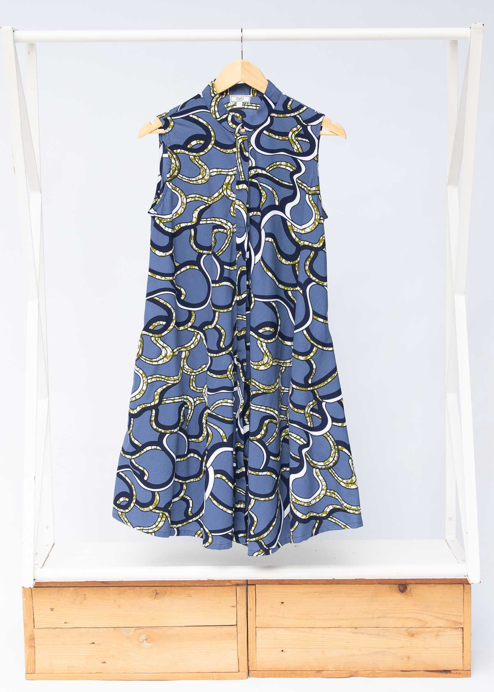 Display of blue sleeveless dress with green, white and navy squiggle design.