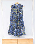 Display of blue sleeveless dress with green, white and navy squiggle design.